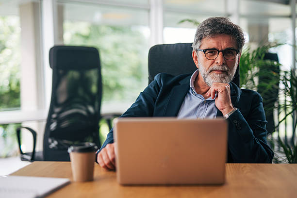 istock Senior businessman working on laptop in modern office 2217338531