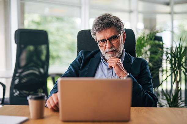 istock Senior businessman working on laptop in modern office 2217338537
