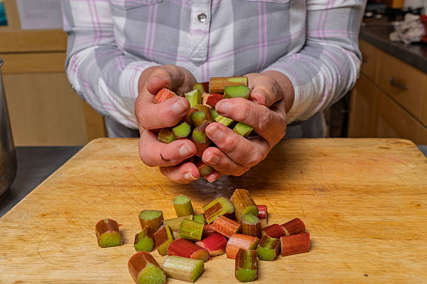 Woman Picks up Chopped Rhubarb on Two Hands from Chopping Board