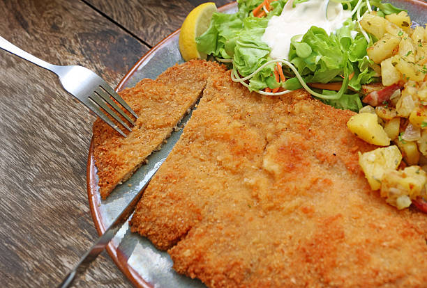 istock Closeup of Knife Cutting Delectable Golden Brown Crispy Schnitzel 2217338732