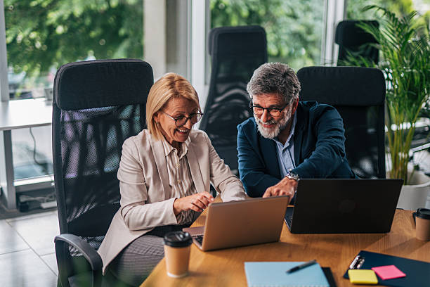 istock Smiling senior colleagues collaborating on laptop in office 2217339016
