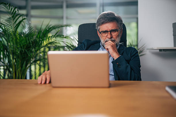 istock Pensive senior businessman working on laptop in office 2217339516
