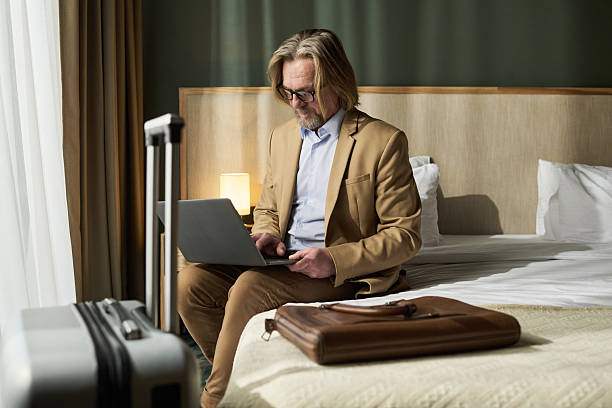istock Elderly Man Working on Laptop in Hotel Room 2217340694