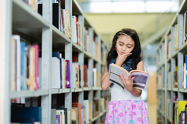 istock Thoughtful elementary age girl reading a book in library 2217341826