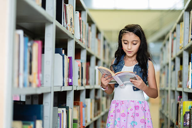 istock Elementary age girl reading a book in the library 2217341958