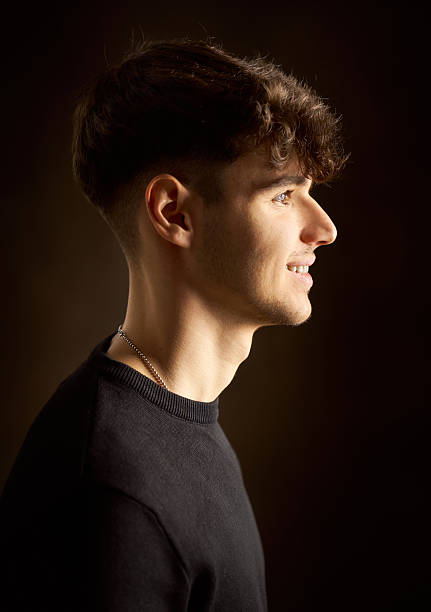 istock Young man smiling and looking away on dark background 2217343441