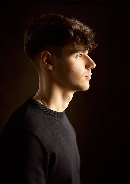 istock Young man posing in profile on dark background 2217343442