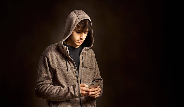 istock Young man wearing a hoodie using smartphone in dark room 2217343458