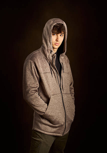 istock Young man wearing hoodie posing in studio with dark background 2217343459