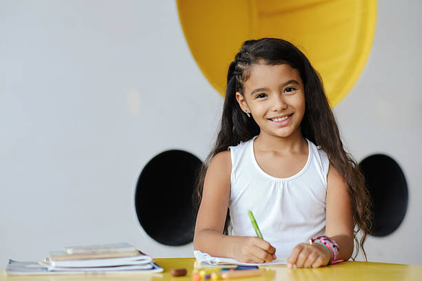 istock Smiling elementary school student drawing at desk in colorful classroom 2217343623