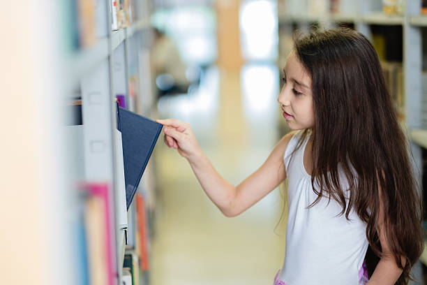 istock Elementary age girl choosing book from library shelf 2217344400