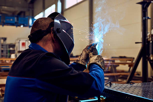 istock Worker Welding Metal in Industrial Workshop with Safety Gear and Bright Sparking Light 2217345059