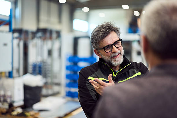Senior Engineer Discussing Ideas With Colleague in a Modern Industrial Setting stock photo