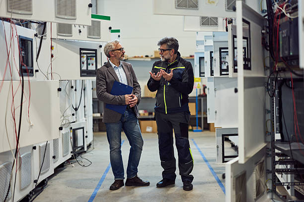 istock Two Colleagues Discussing in an Industrial Workshop Filled With Equipment 2217345107