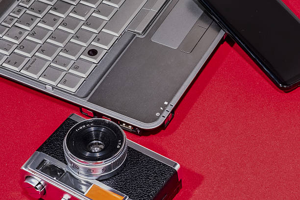 istock Laptop, vintage camera, and cellphone create a study in contrasts on a textured red background. 2217345275