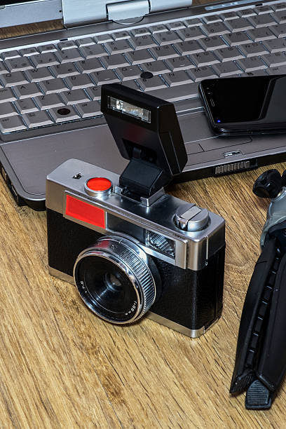 istock Vintage camera with a flash sits on a laptop next to a smartphone and a tripod. 2217345443