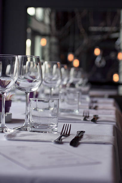 istock Fine dining restaurant table set with sparkling wine glasses, old fashioned glasses, and pristine white napkins, viewed from low angle creating an elegant perspective. 2217345793