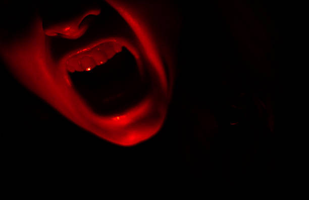 istock Creepy screaming red mouth on black background 2217347790