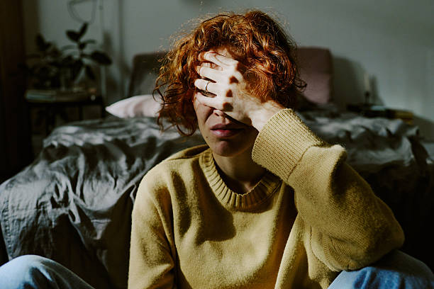 istock Sitting in Bed Covering Face with Hand in Intimate Setting 2217348767