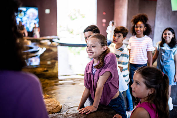 istock Child students talking and interacting with marine life in touch pool at aquarium 2217349434