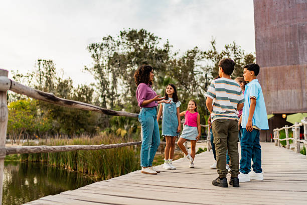istock Young teacher talking to child students during field trip on zoo 2217349515