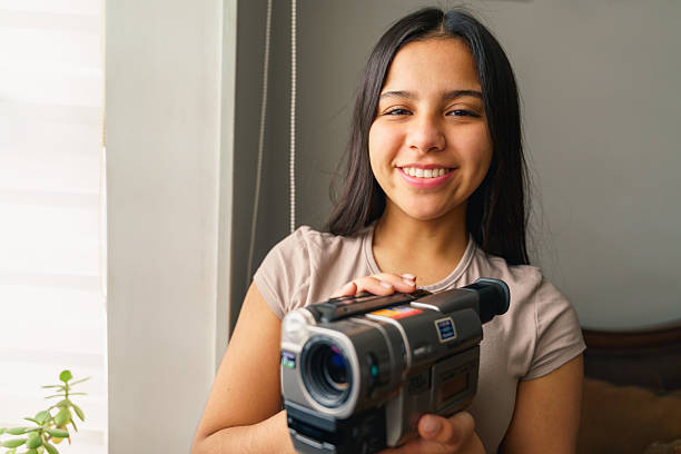 Young hispanic woman smiling and holding a camcorder, recording a video blog or online content
