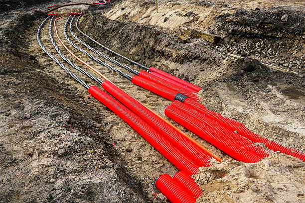 istock Laying new underground high-voltage power cable in red corrugated protective tube 2217355891