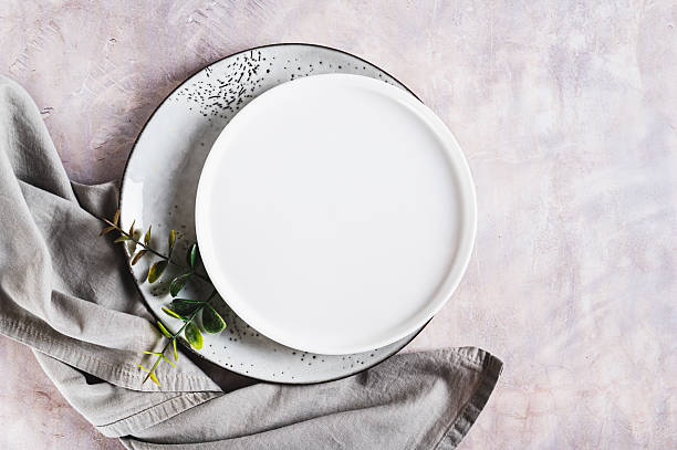 istock Pair of empty ceramic plates with napkin on gray background top view 2217356122