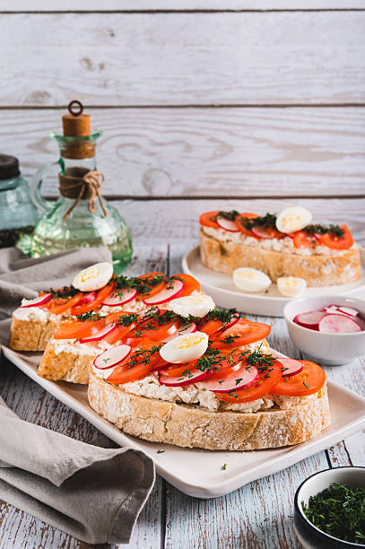 istock Appetizing bruschetta with ricotta, tomato, radish and quail egg on a plate vertical view 2217356544