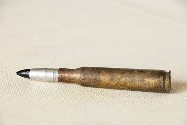 Single large caliber cartridge on light fabric, military theme