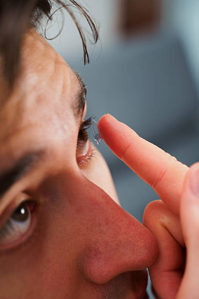 istock Man inserts a contact lens into eye for myopia treatment. Correcting eye wellnesses with optical contact lenses. 2217357676