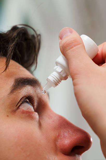 istock Man drips eye with eyes drops due to irritation problem. Applying eye drops for eye vision treatment at home. 2217357715