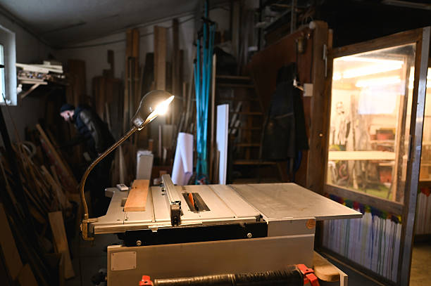 istock Table saw illuminated by a lamp in a messy carpentry workshop. 2217359921