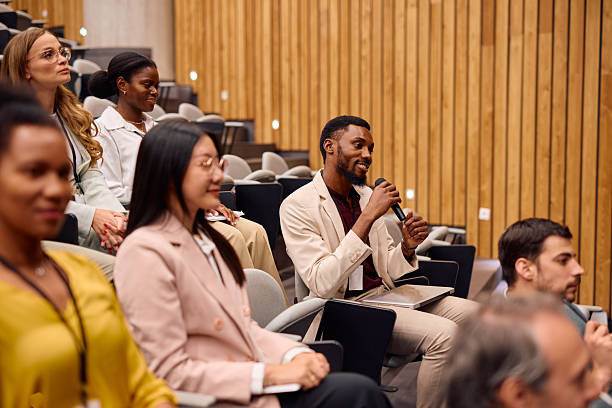 istock Young businessman asking a question during a conference in a modern auditorium 2217360149