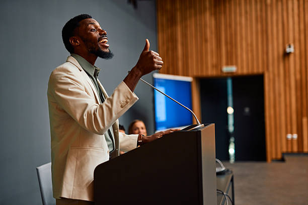 istock Motivational speaker inspiring audience with thumbs up gesture during conference 2217360183