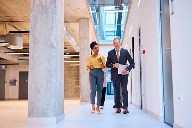 istock Business partners walking and talking in modern office hallway 2217360510