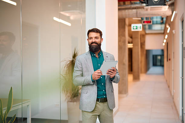istock Businessman smiling and holding digital tablet in office corridor 2217360720
