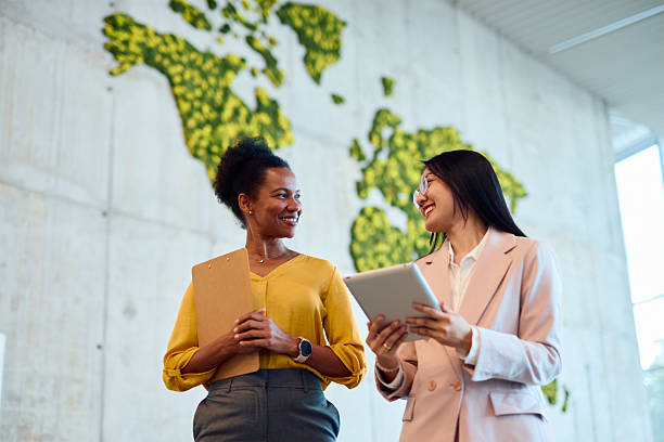 istock Businesswomen discussing work in modern office with vertical garden world map 2217360745