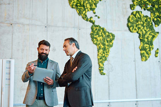 istock Businessmen discussing a project in a modern office with a world map 2217360833