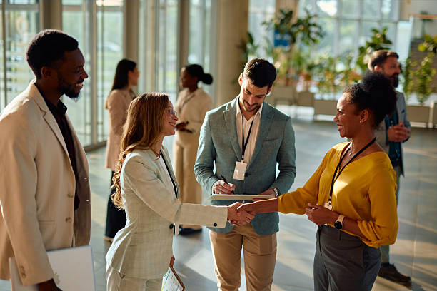 istock Businesswomen shaking hands at a corporate event while a businessman takes notes 2217361099