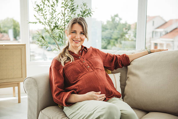 Portrait of beautiful pregnant woman sitting on couch at home.