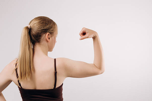 istock Strong woman flexing her bicep with a confident pose, showcasing physical strength and empowerment, with a neutral background emphasizing her muscular definition and determination in action 2217363700