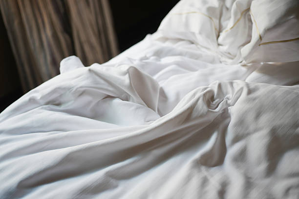 istock Soft white bedding on a neatly arranged bed in a cozy space 2217363797