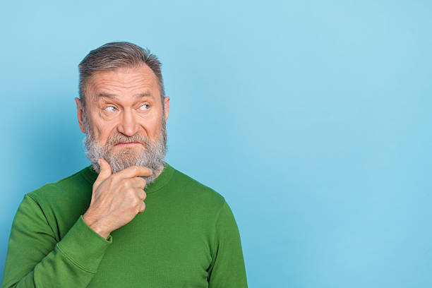 istock Photo of skeptic middle aged man touch chin empty space try decide brainstorming idea isolated blue color background 2217365787