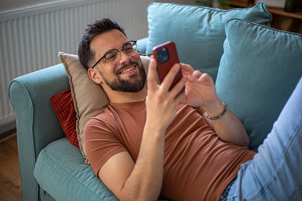 istock Young man relaxing on sofa using smartphone, enjoying leisure time at home 2217365850