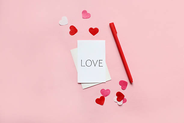 istock Envelope with blank white paper card for copy space, red hearts and candies over pink background 2217367176