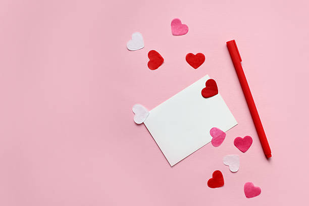 istock Envelope with blank white paper card for copy space, red hearts and candies over pink background 2217367177