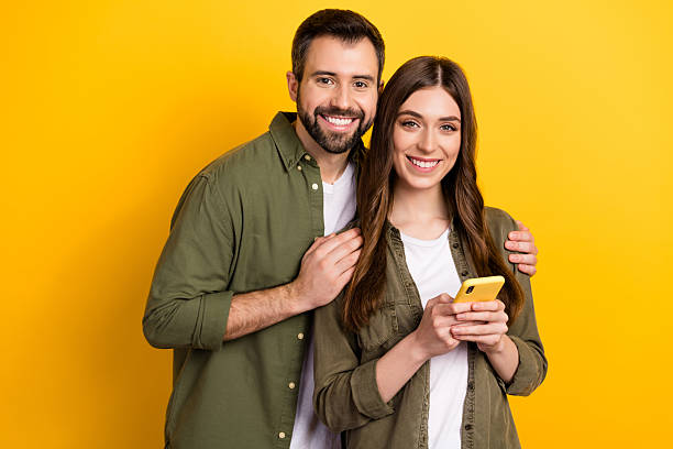 istock Portrait of attractive cheerful couple using device surfing web app 5g isolated over bright yellow color background 2217367774