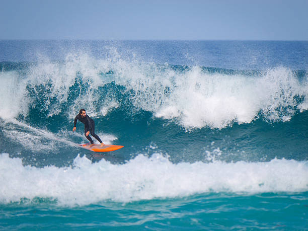 istock Surfer rides low on an orange board trying to escape a closing powerful wave 2217370271