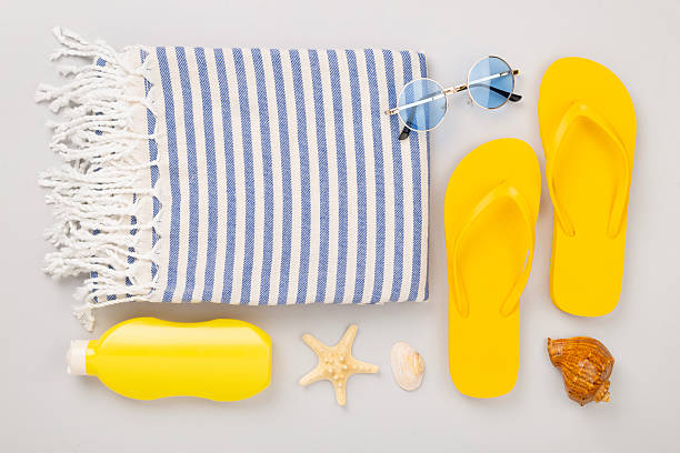 Beach towel with summer accessories on color background, top view